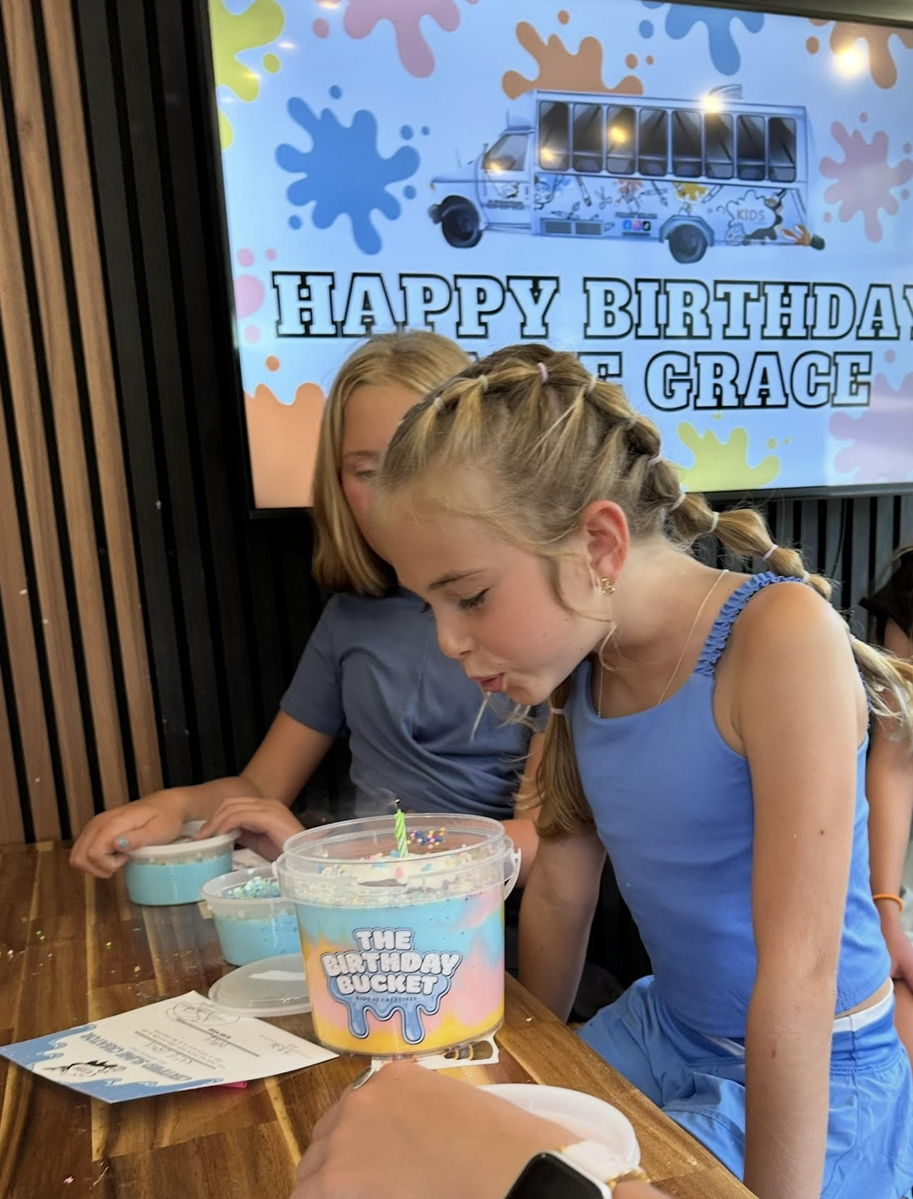 Kids with their slime Birthday Buckets in front of a Happy Birthday party backdrop