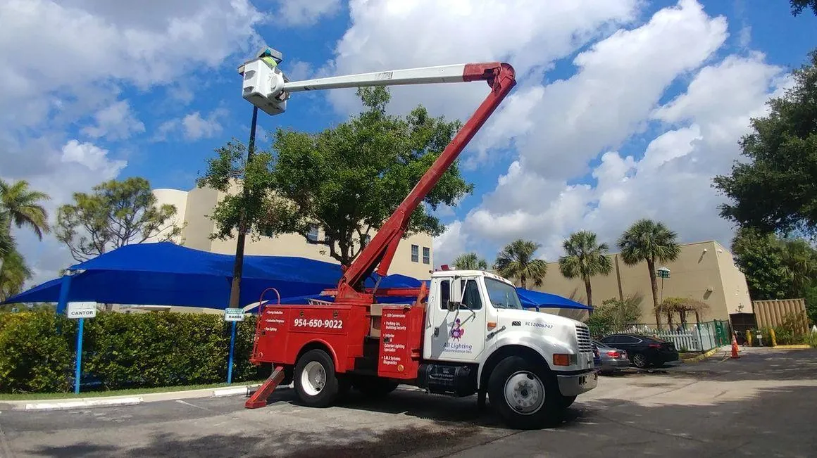 All Lighting Maintenance bucket truck in operation repairing a parking lot pole light in Florida.