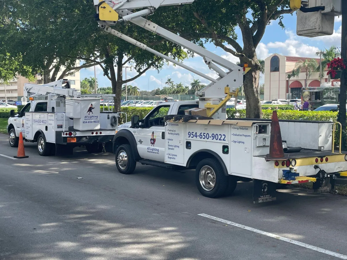A fleet of All Lighting Maintenance bucket trucks stationed on-site for a large-scale commercial lighting repair project in Florida.