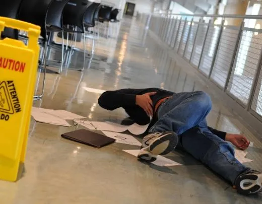 Man on floor after a slip and fall, with a wet floor sign visible; seek expert representation from The Mitchell Law Firm, your Florida Board Certified Civil Trial Specialist for premises liability.