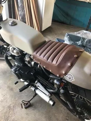 Custom brown leather motorcycle seat with ribbed tuck-and-roll upholstery and silver rivets, handcrafted by AE Auto Upholstery in Melbourne, FL.