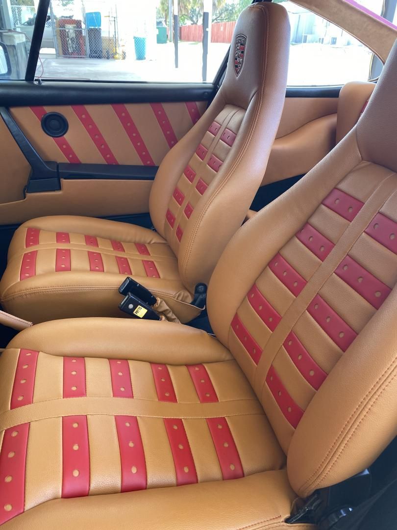 Luxury Porsche 911 custom leather interior restoration with red perforated inserts and embossed headrests by AE Auto Upholstery in Melbourne, Florida.