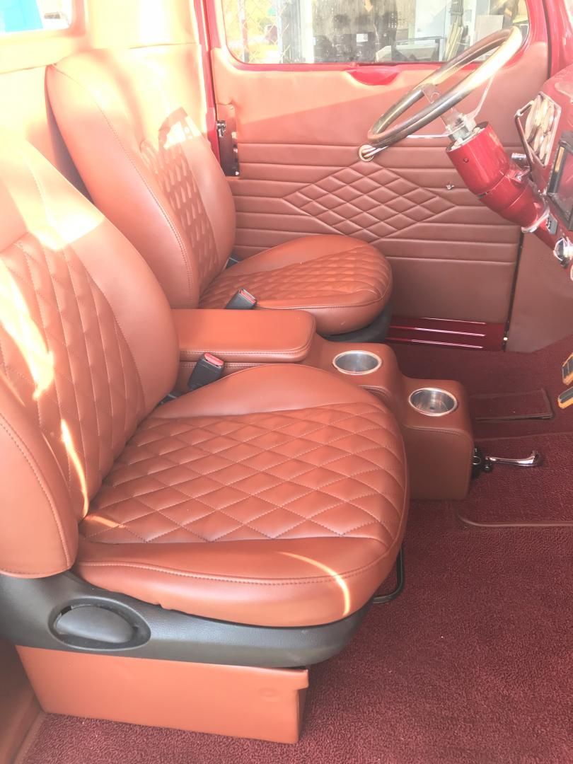Custom brown leather restomod truck interior featuring diamond-stitched bucket seats, a fabricated center console with cup holders, and matching door panels by AE Auto Upholstery in Melbourne, Florida.
