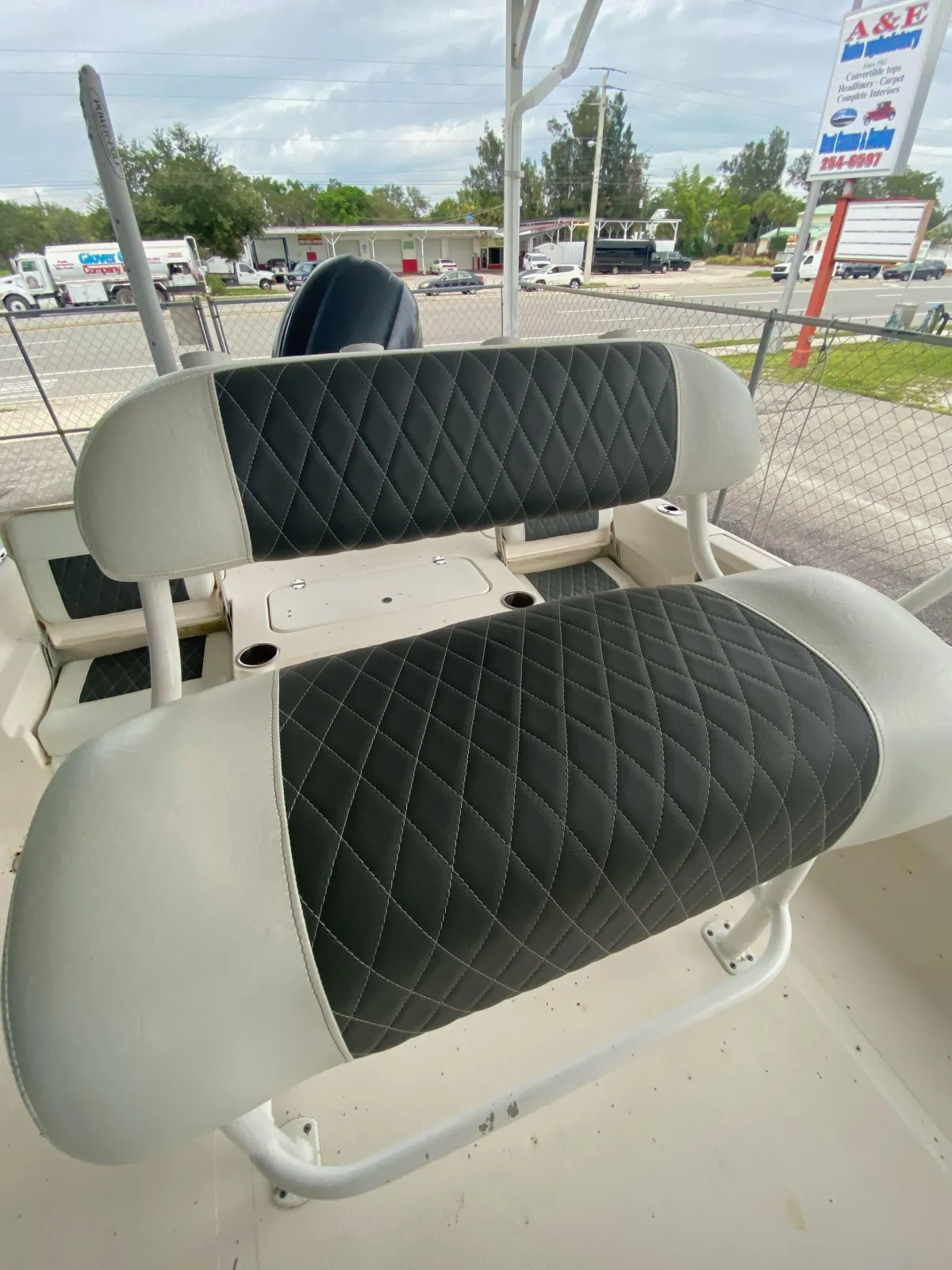 Custom white marine vinyl leaning post and bench seat with black diamond-stitched inserts for a center console boat, crafted in Melbourne, FL.