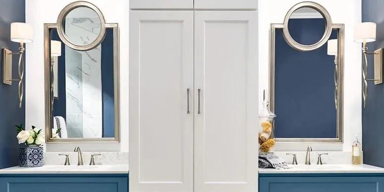 Master bathroom featuring navy blue double vanities, white floor-to-ceiling linen cabinets, and large silver-framed mirrors with marble countertops.