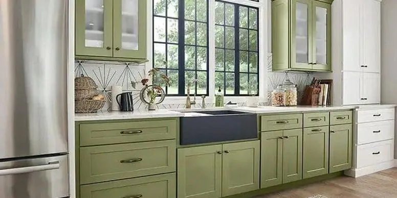 Modern farmhouse kitchen with sage green shaker cabinets, a black apron-front farmhouse sink, and geometric tile backsplash.