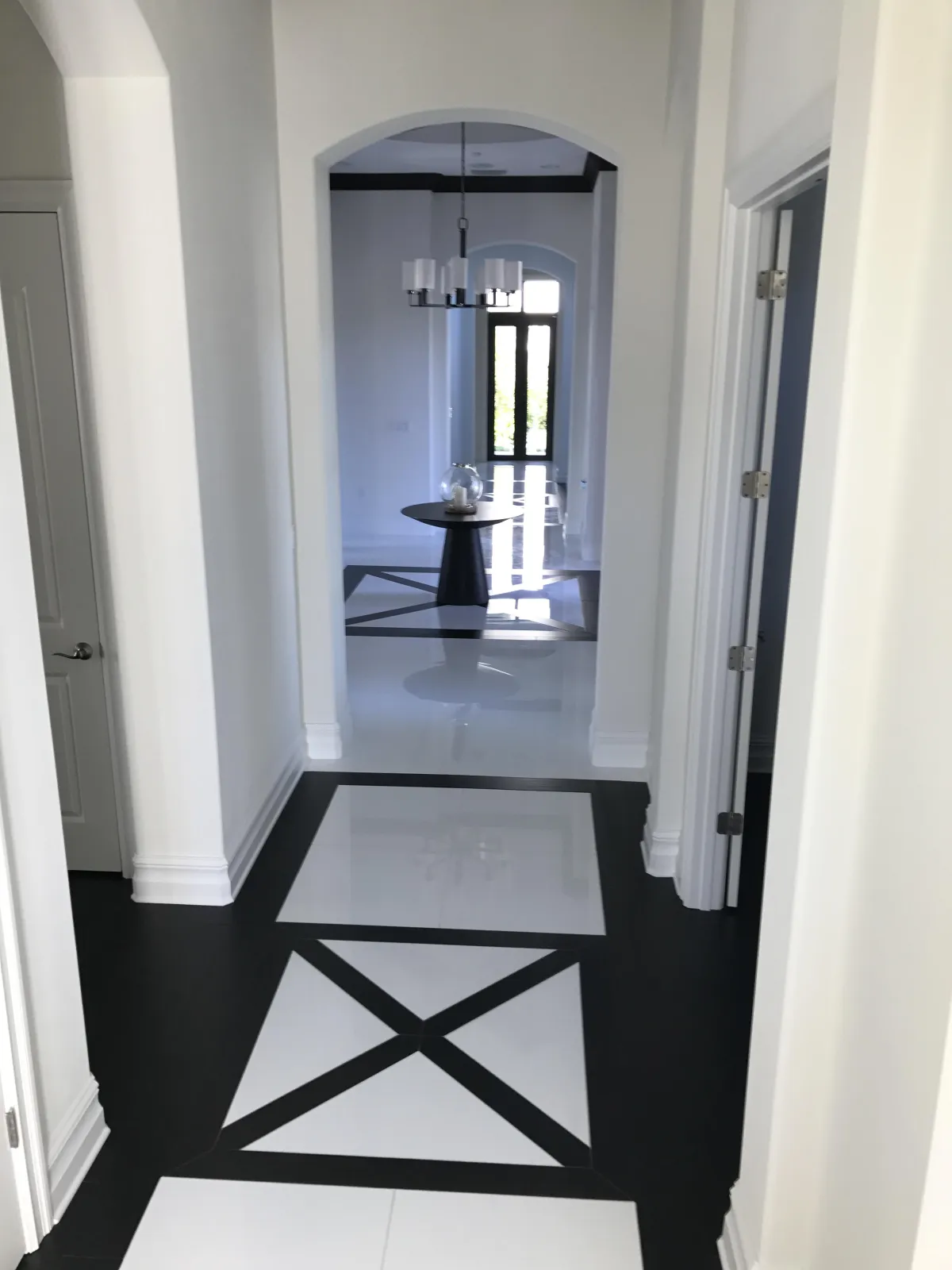 Modern grand entryway featuring a custom geometric black and white tile floor inlay with high-gloss porcelain tiles.