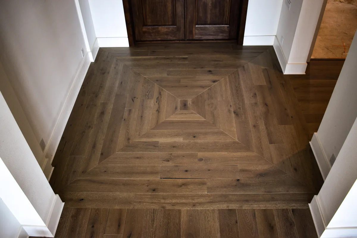 Luxury entryway featuring a custom geometric wood floor inlay made of medium-tone oak planks in a square pattern.
