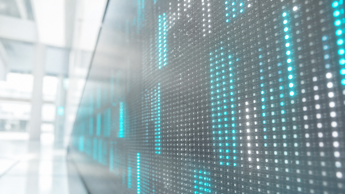 Digital ticker board with some AI stocks dimmed, others bright, under cyan light.