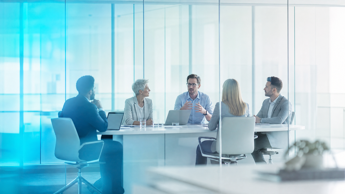 Executives in a glass-walled boardroom with cyan lighting