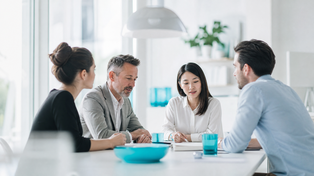 Business team discussing at a table with cyan-colored items in a bright office.